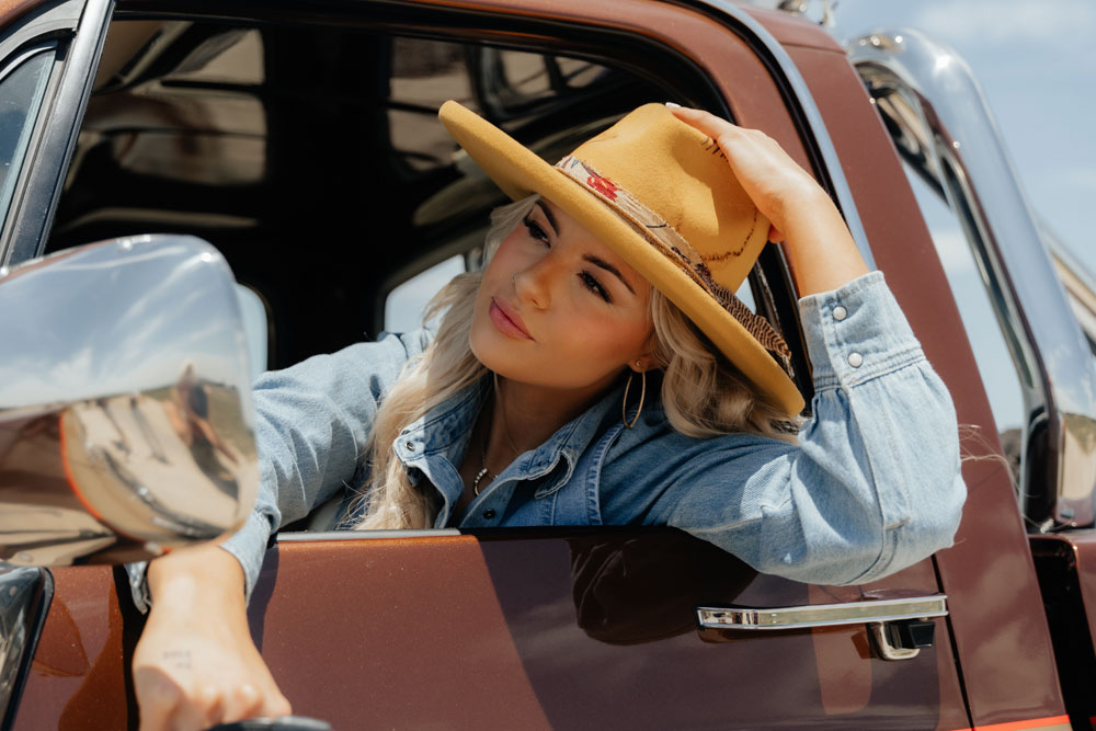 A woman wearing a cowboy hat while sitting in a pickup truck.